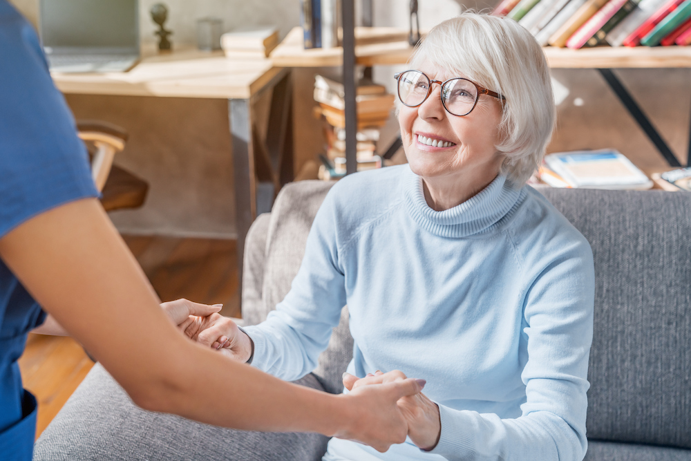 Cropped image of female professional caregiver taking care of elderly woman at home